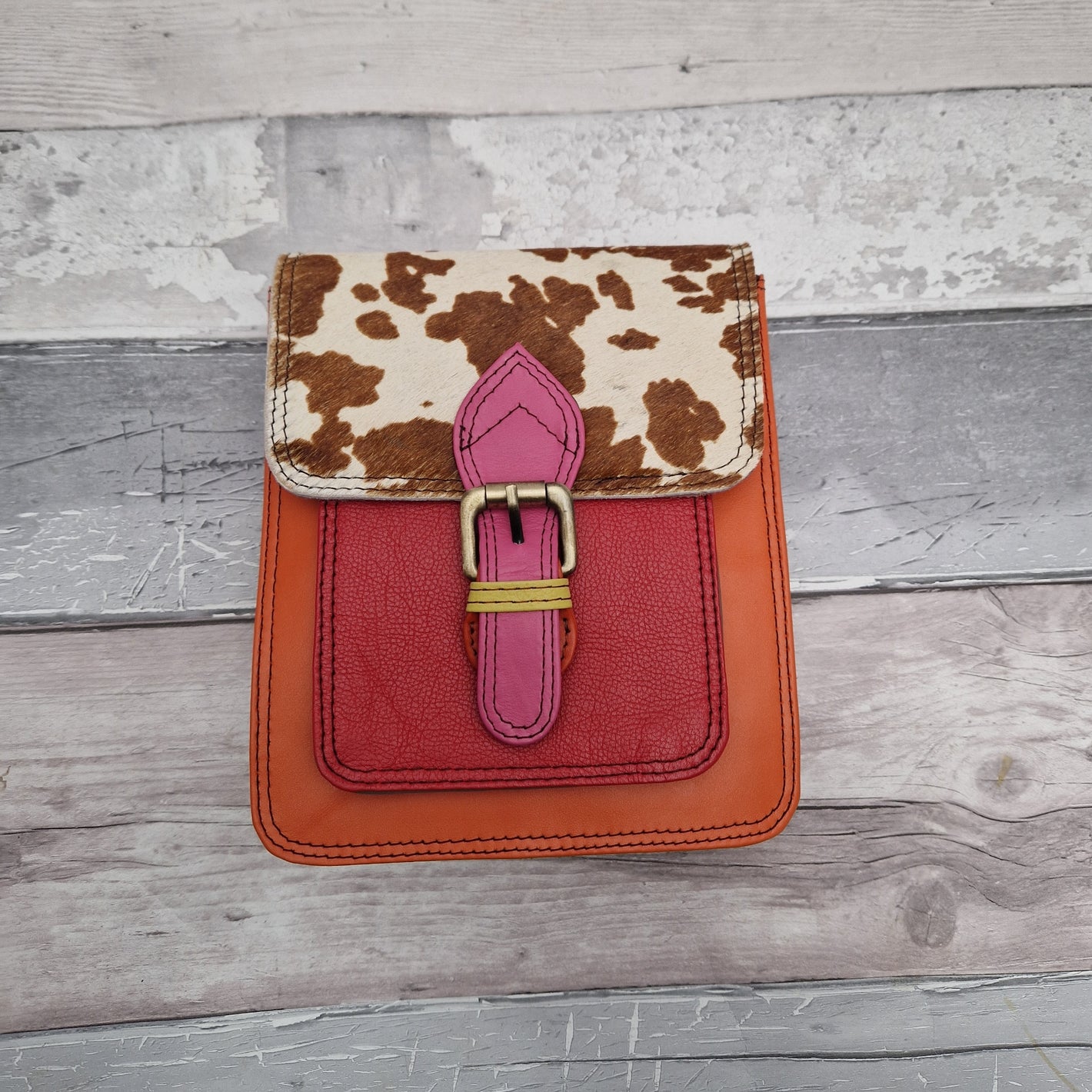 Orange leather messenger style bag decorated with a panel in textured cow hide.