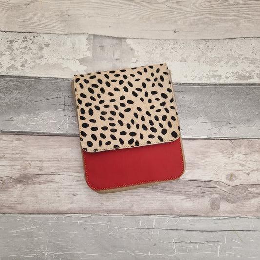 Leather cross body bag with a red leather front and a textured panel in a black and white spot print.