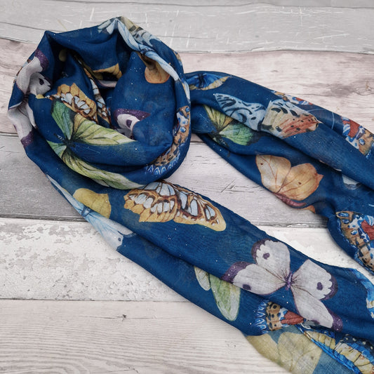 Ocean blue scarf decorated with a collection of vividly coloured butterflies and finished with silver sparkles.