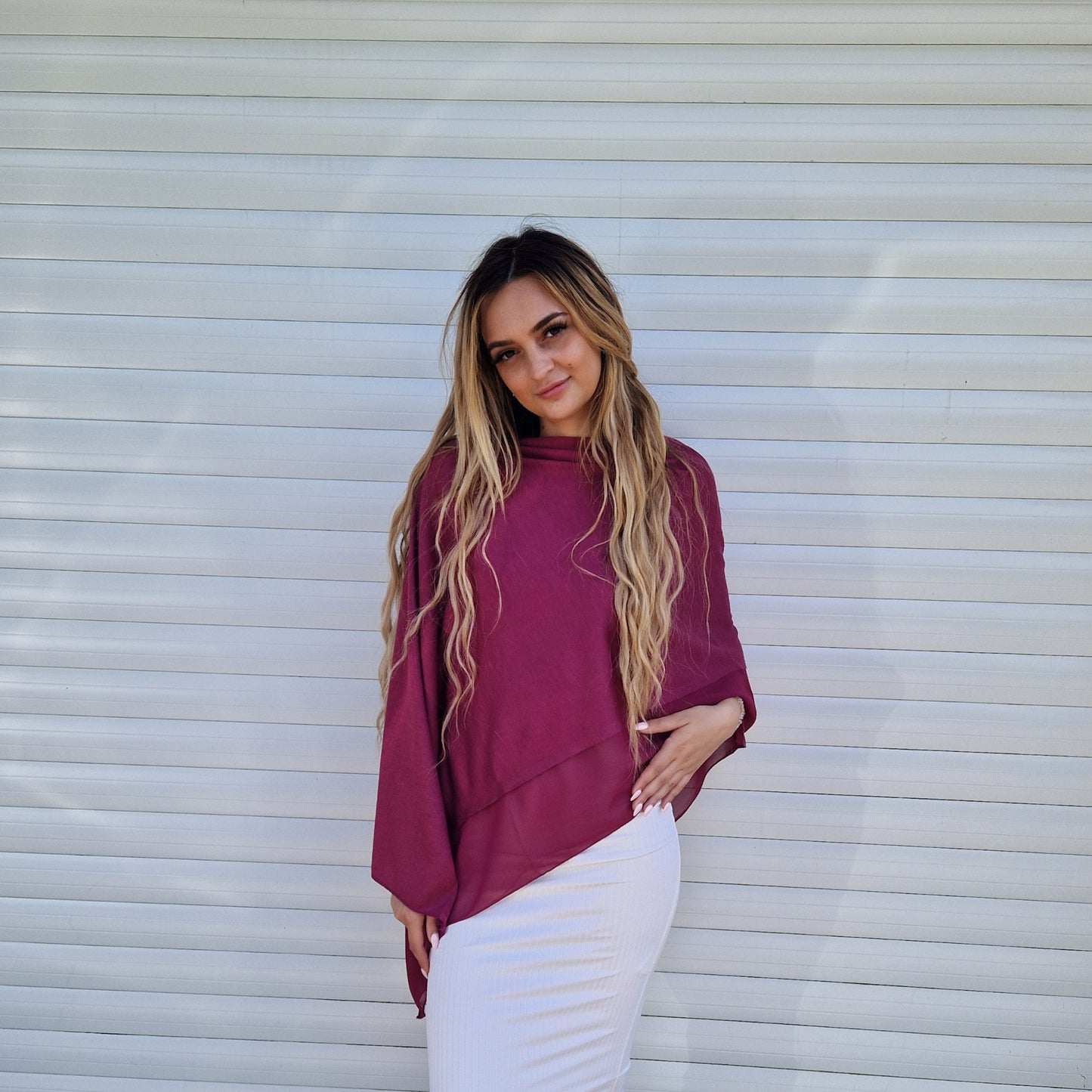 Young lady wearing a burgundy coloured poncho with chiffon trim.