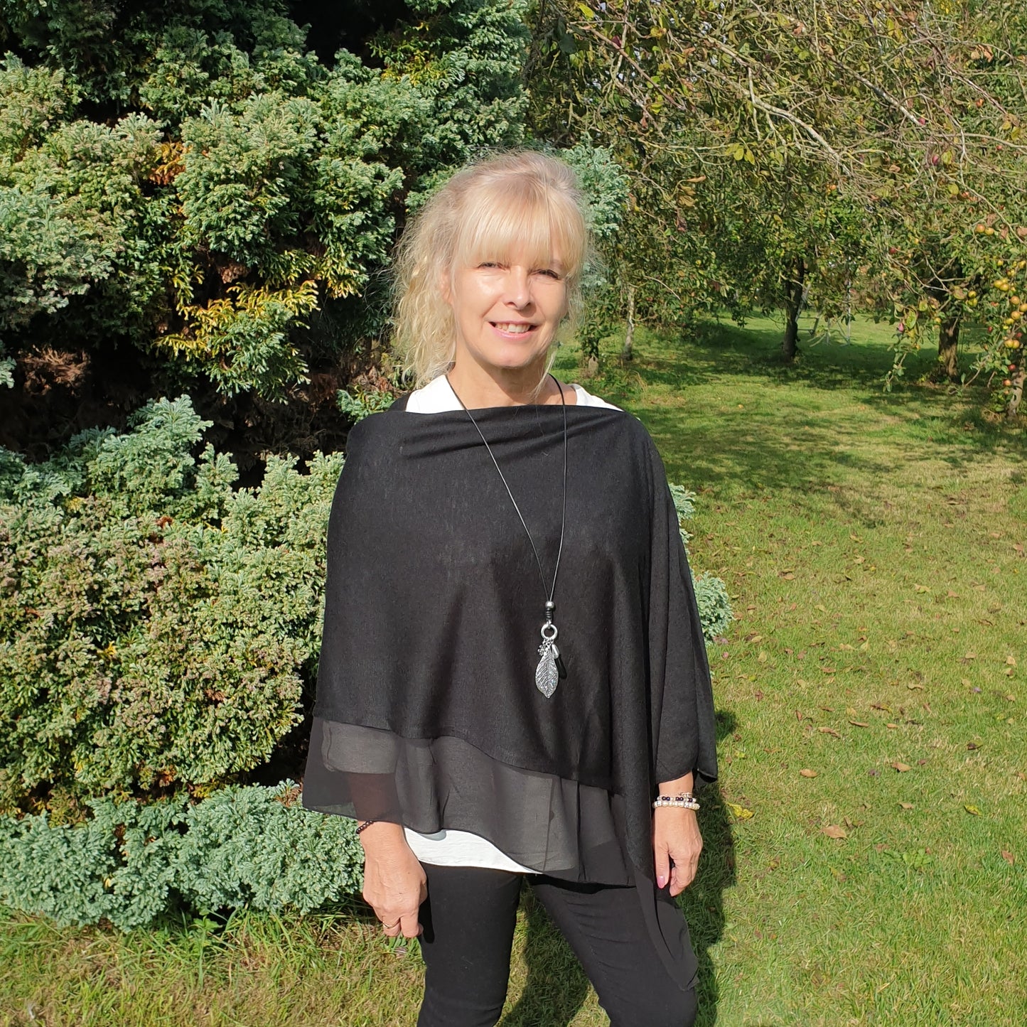 Lady wearing a black poncho with chiffon trim.