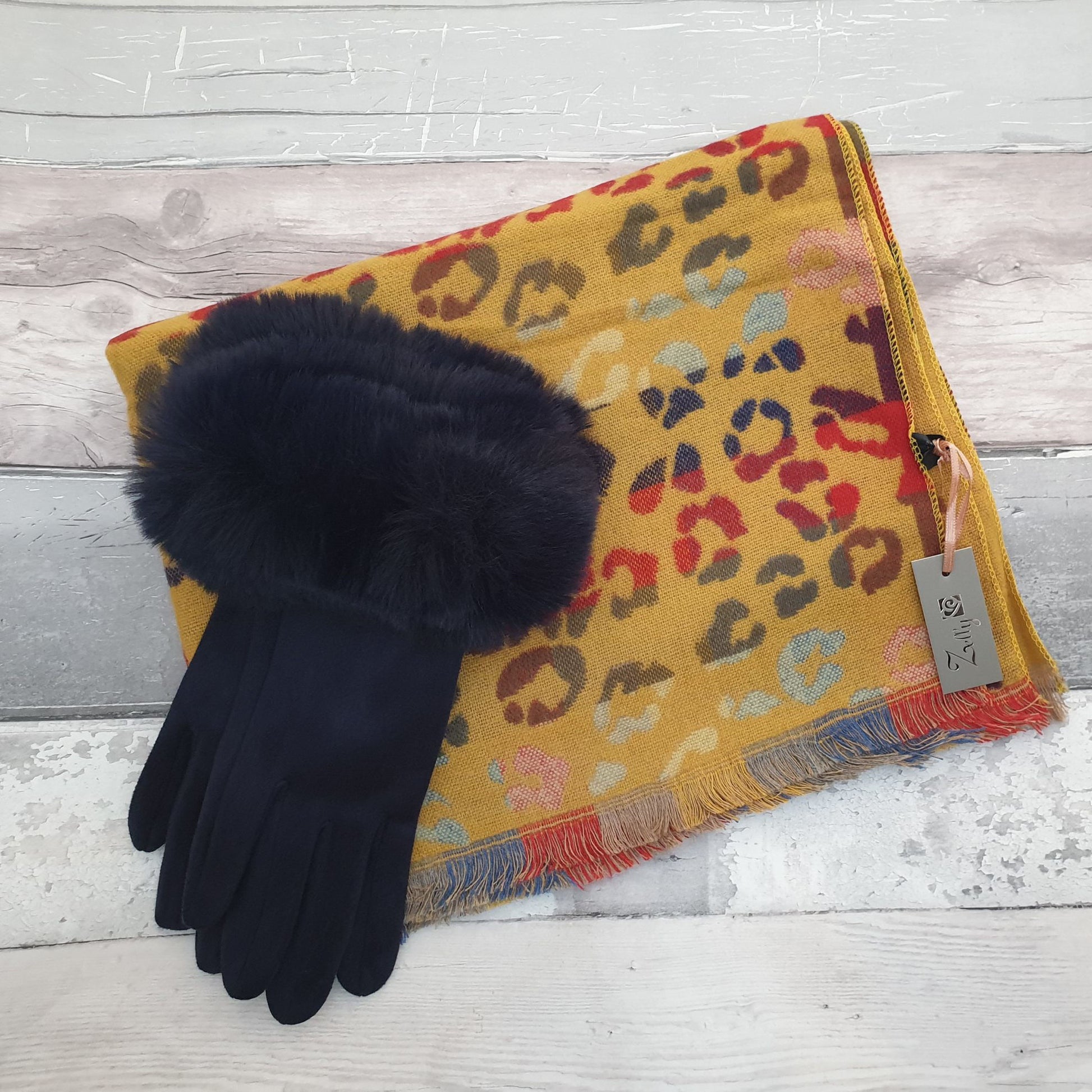 Photo of a mustard coloured animal print scarf with rainbow colours and a pair of matching mustard coloured gloves