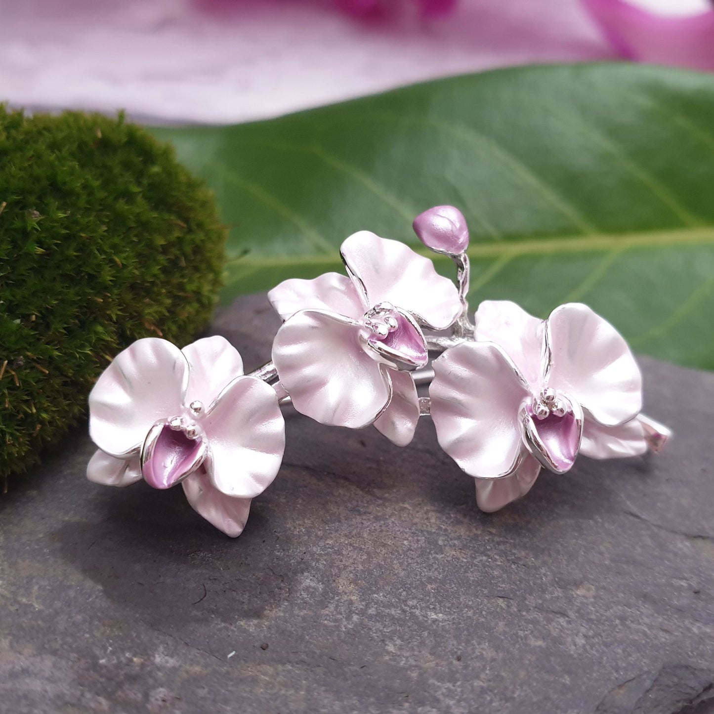 Photo of a spray of pink orchid flowers on a silver stem as a ladies brooch