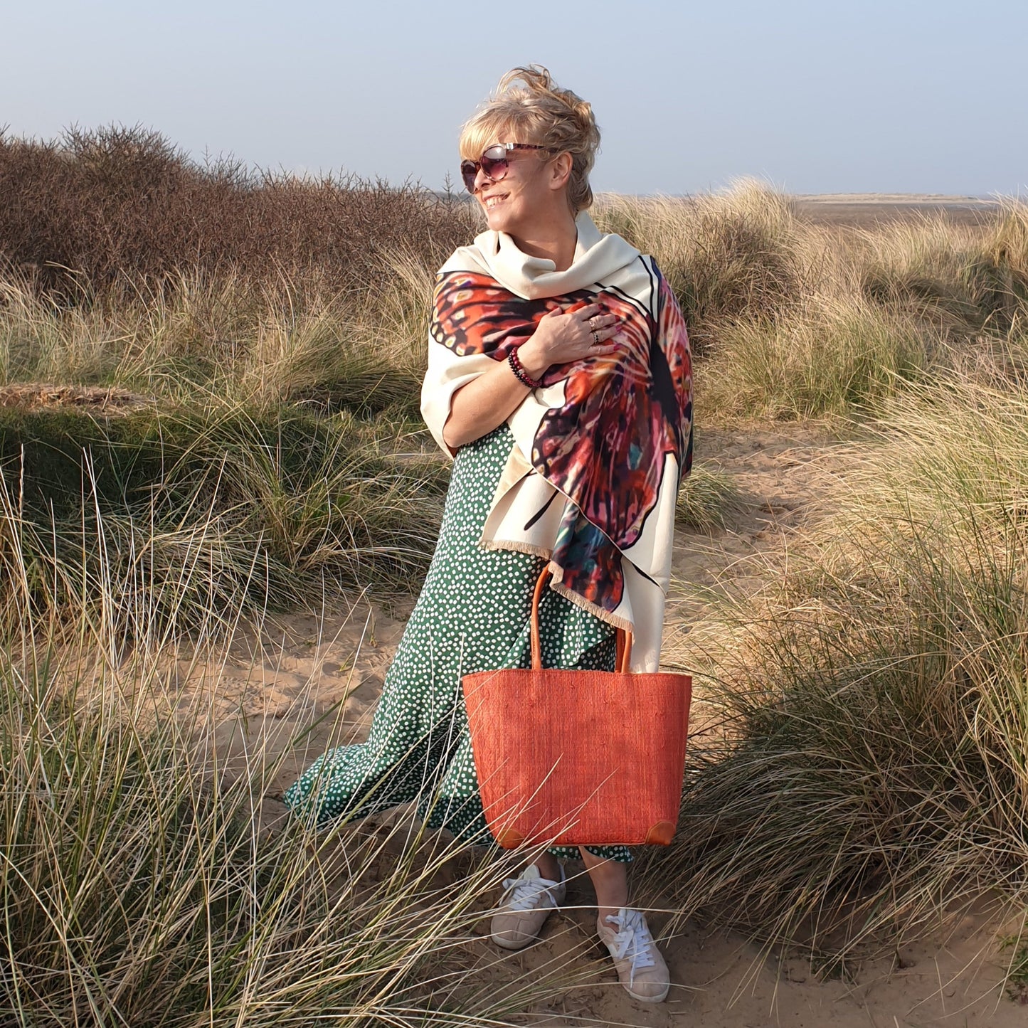 Lady on the beach carrying a red raffia basket 