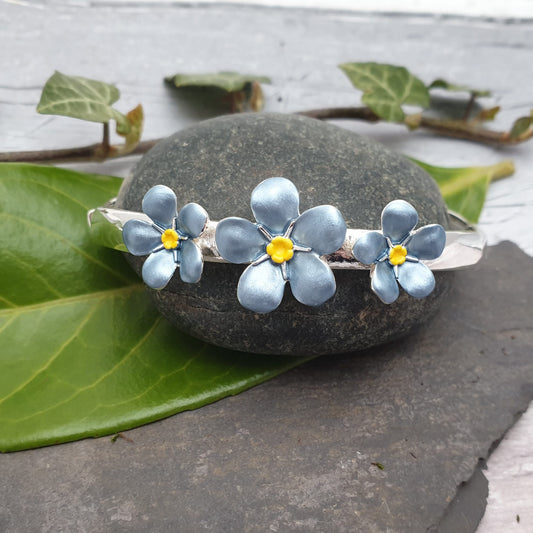 Stretch bracelet in a silver finished surround with 3 Forget-me-not flowers across the top.