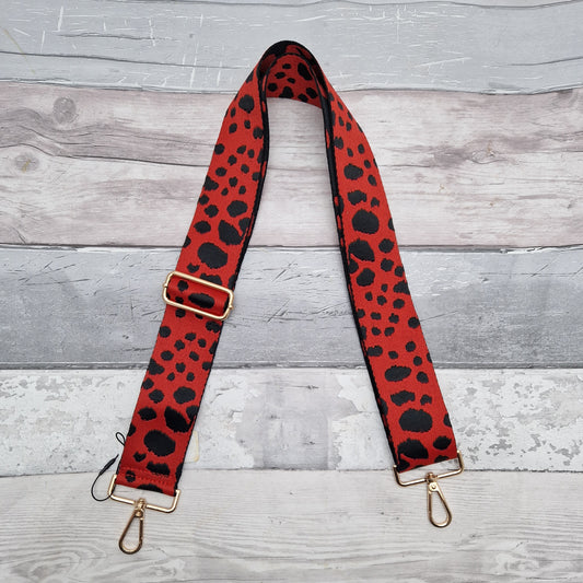 Red Cross body bag strap decorated with irregular black spots.