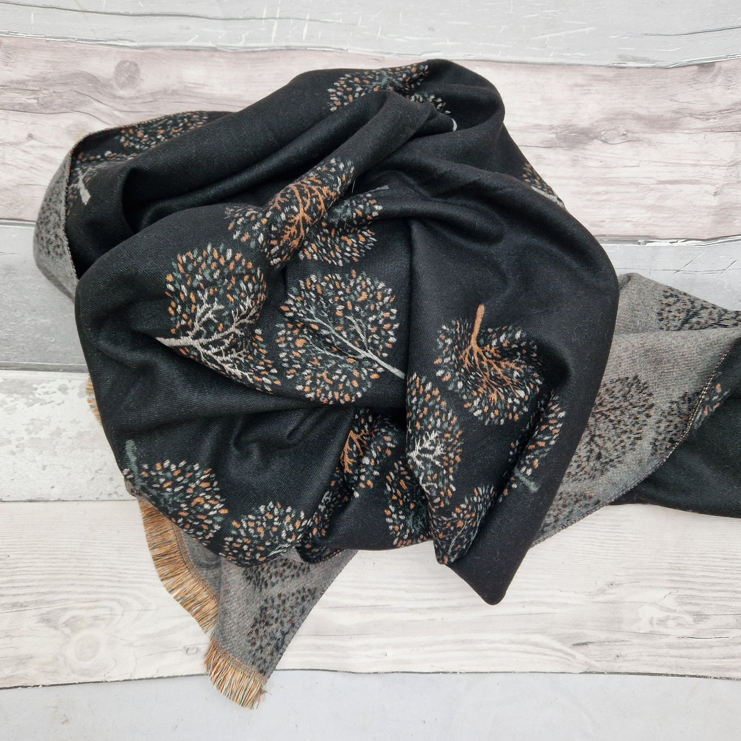 Black scarf with trees of life depicted in warn tones of orange and coffee colours