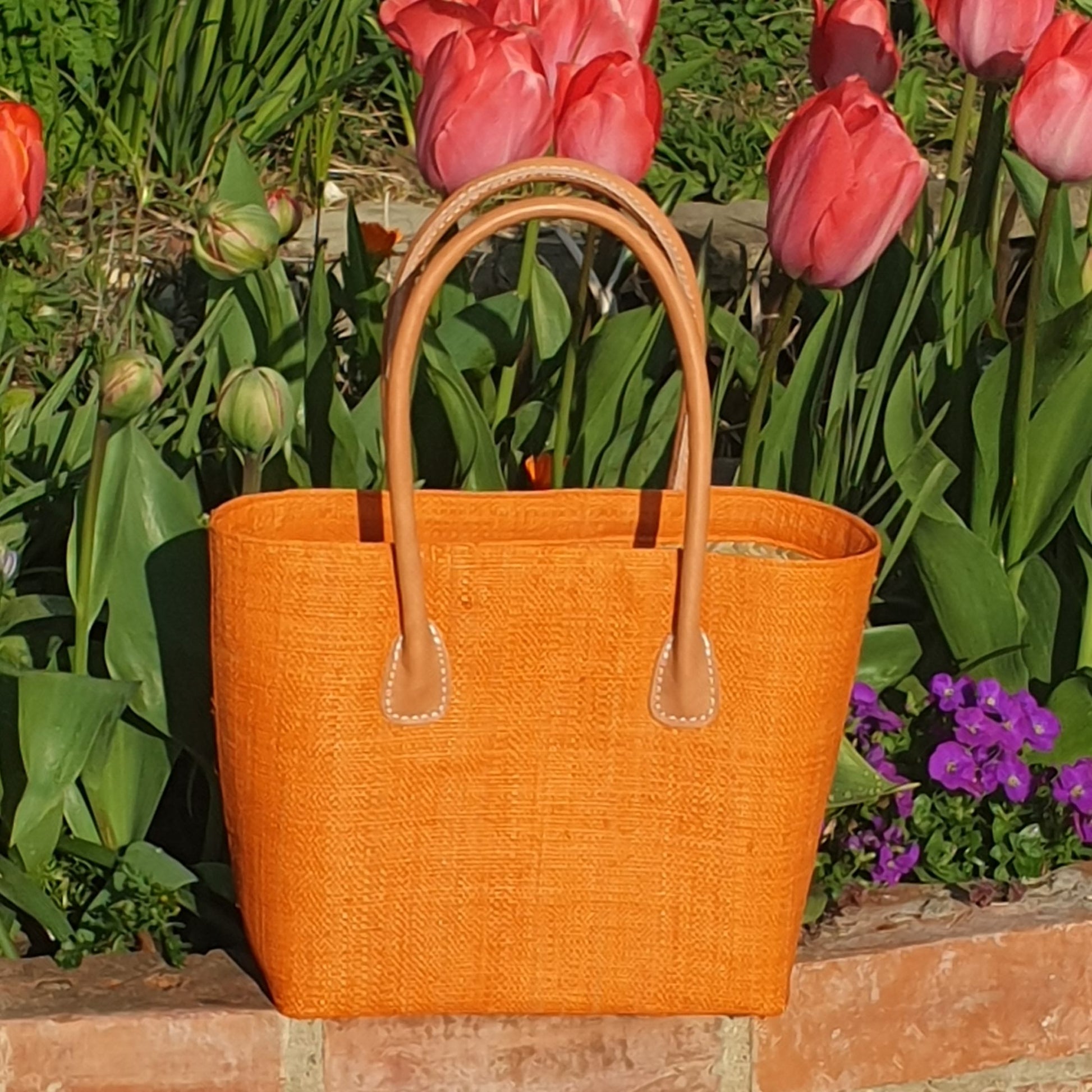 Bright orange raffia basket with leather handles