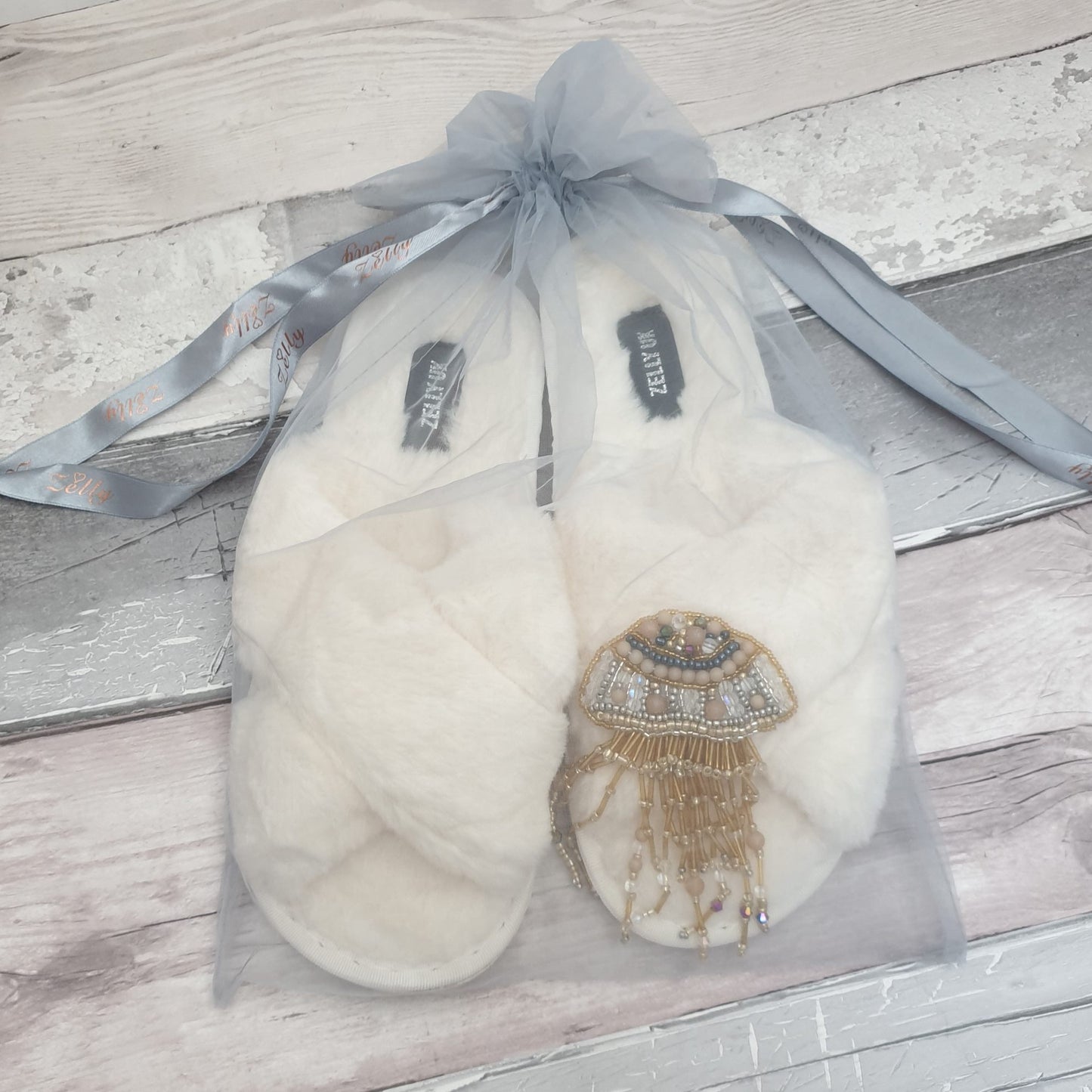 White fluffy slipper with jellyfish brooch in a grey organza bag