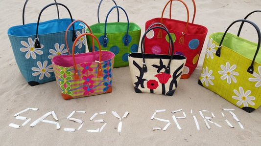 Brightly coloured Sassy Spirit Raffia Baskets on the beach
