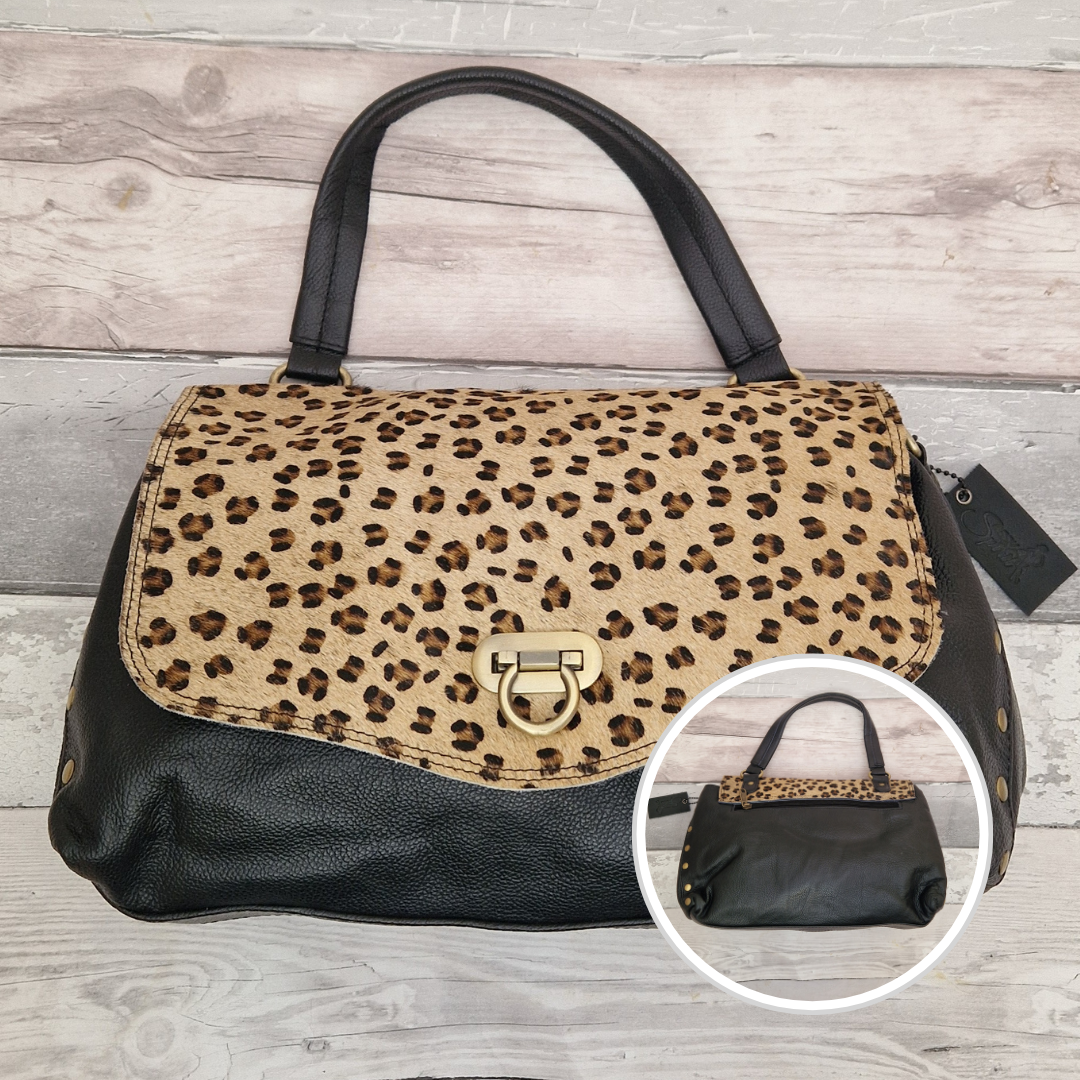 Leopard print handbag with black leather accents on a wooden surface