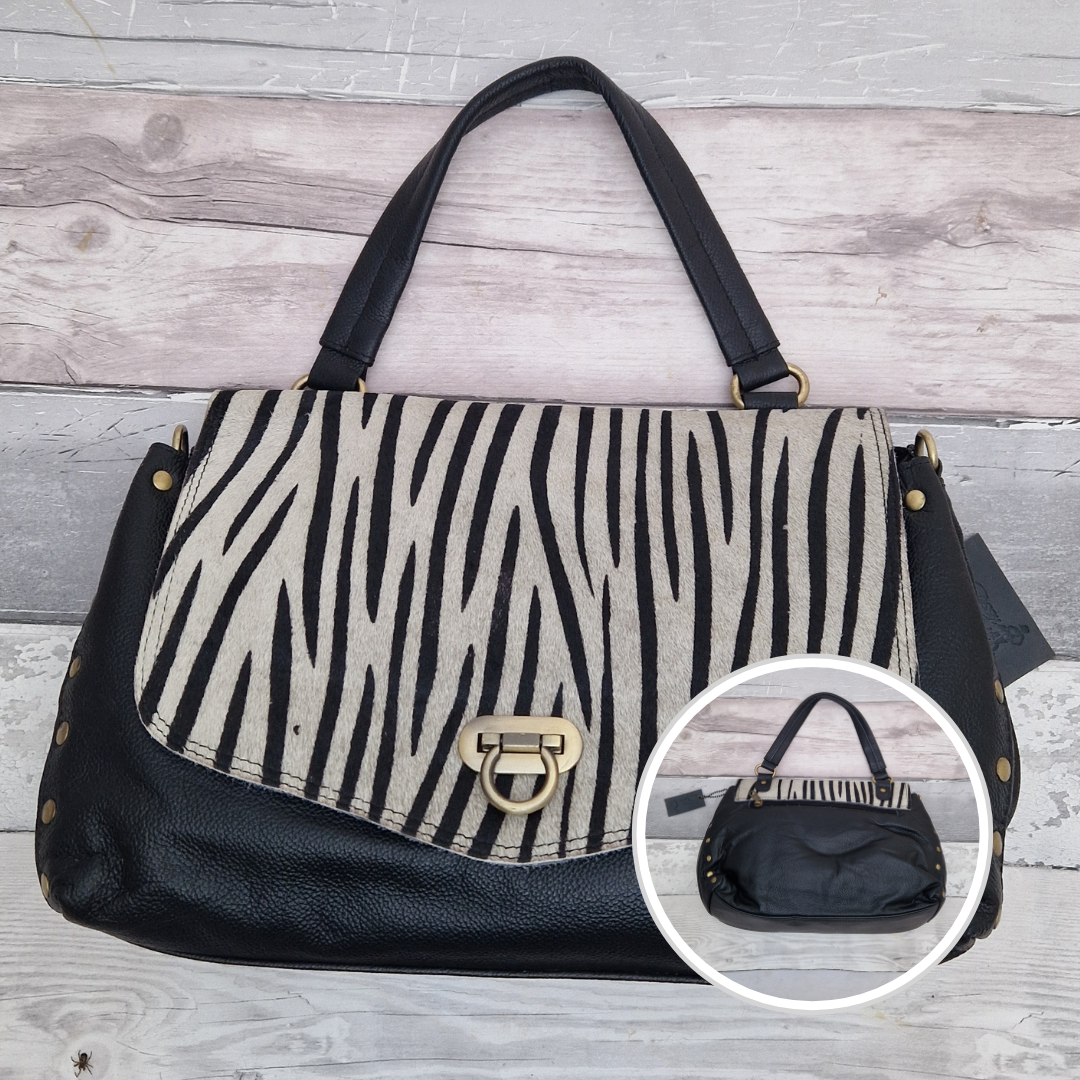 Zebra print handbag with black accents on a wooden surface