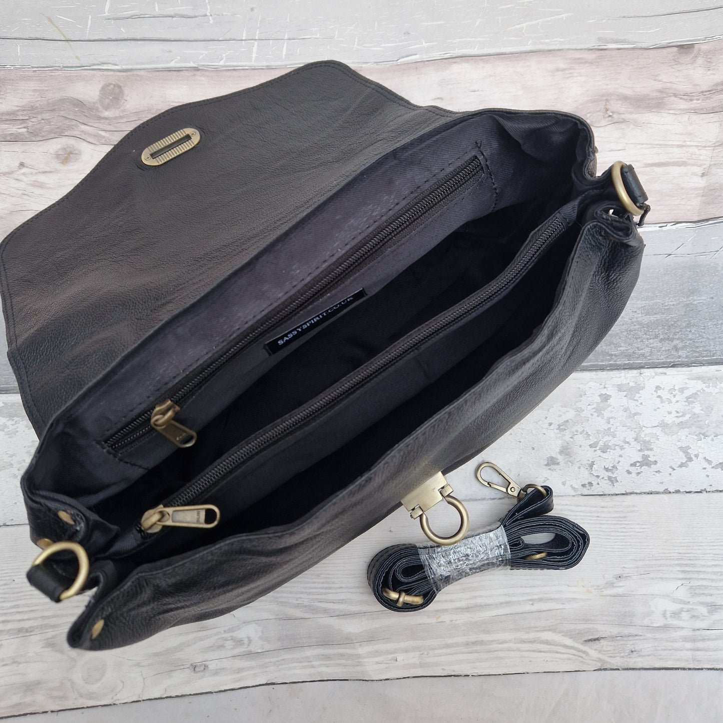 Black bag with gold zippers on a wooden surface