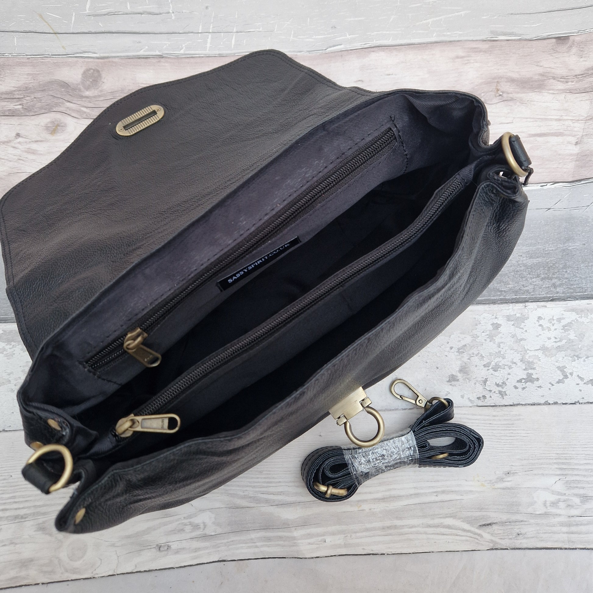 Black bag with gold zippers on a wooden surface