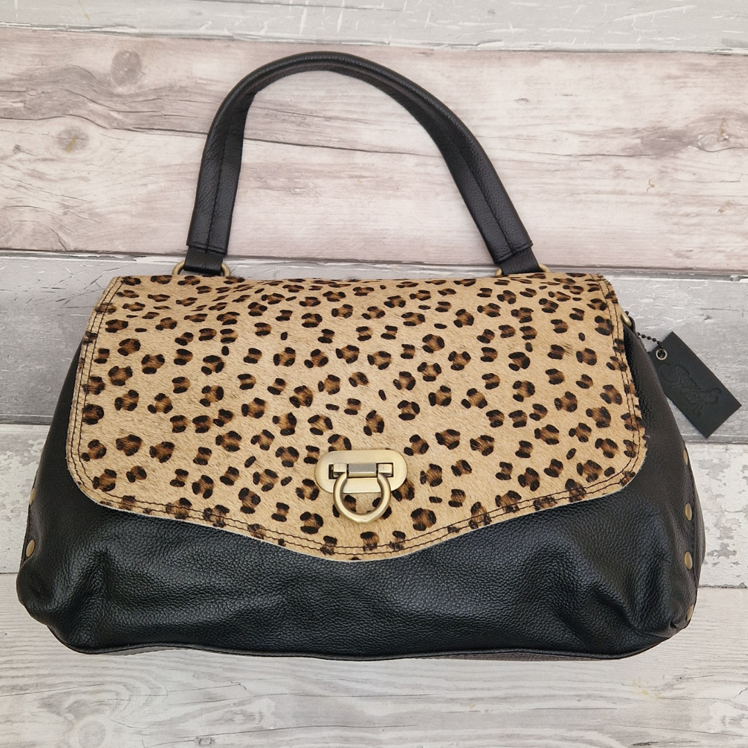 Black baguette shaped leather bag with a carrying handle and a front panel of textured leopard print.