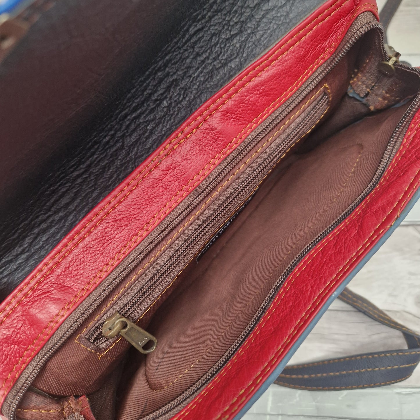 Red leather bag with a zipper on a wooden surface