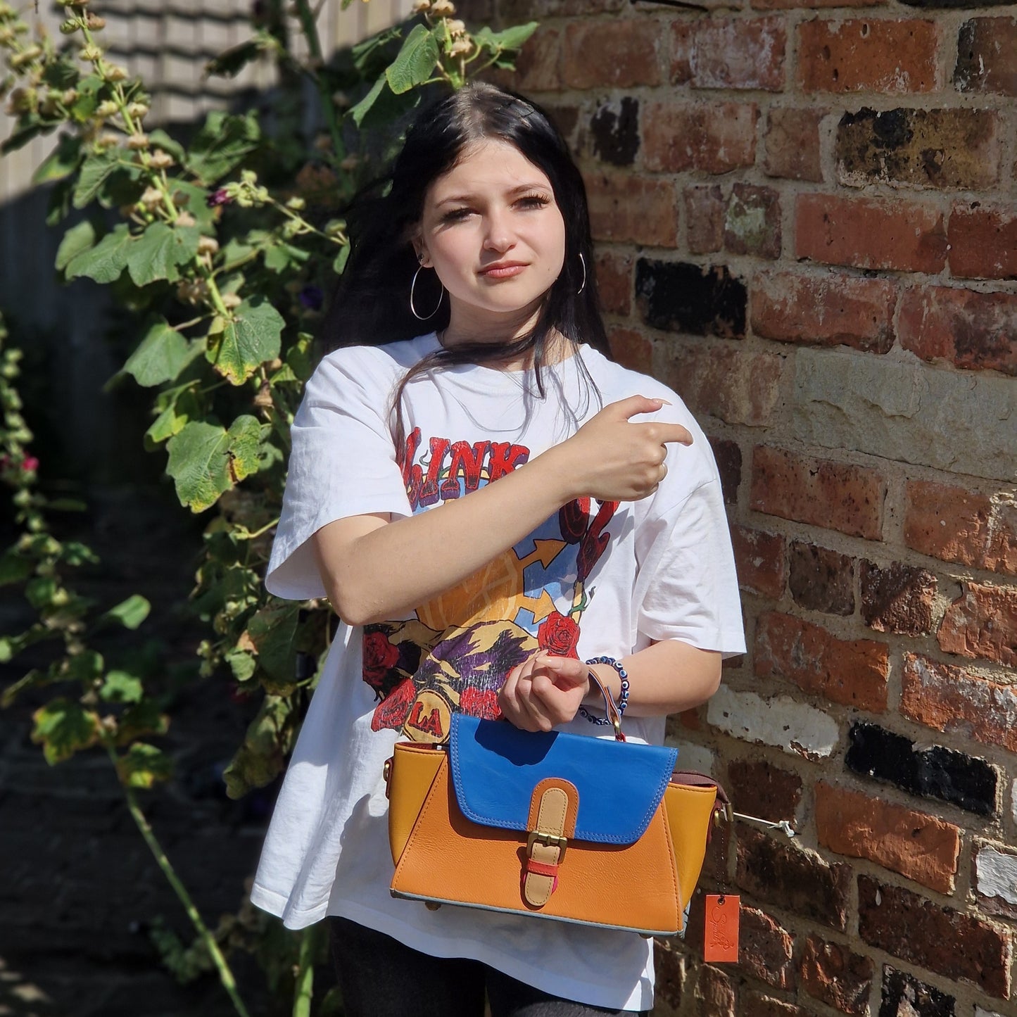 Model holding Sassy Spirit Jhansi handbag in blue and mustard tones.