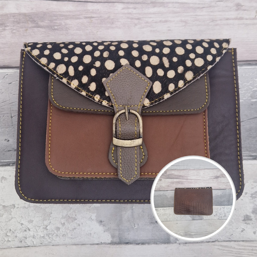 Mini satchel style crossbody bag made with in aubergine with contrasting coloured panels, a buckle closing tab and a textured panel of spot print.