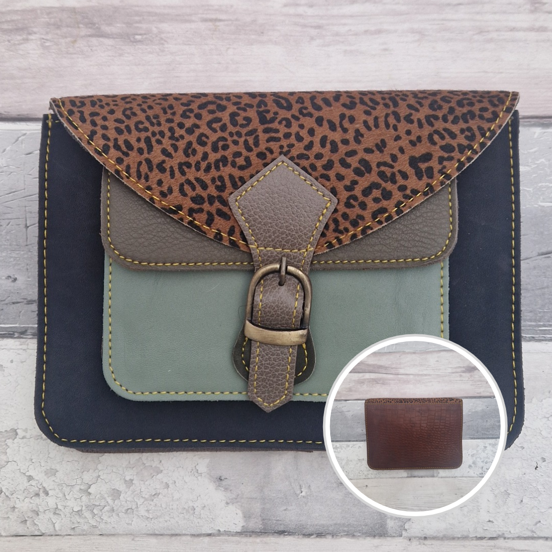 Mini satchel style crossbody bag made with in navy with contrasting coloured panels, a buckle closing tab and a textured panel of cheetah print.