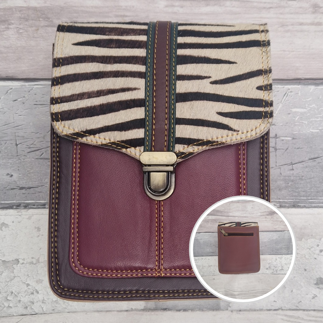 Wine leather crossbody bag with a textured panel of zebra print. Accessed via a push clasp.