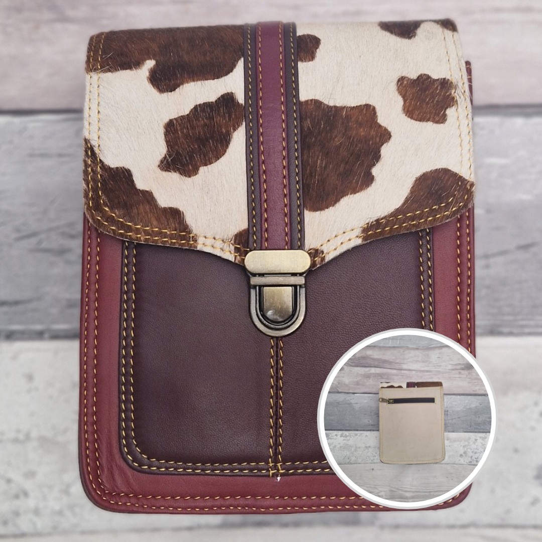 Raspberry leather crossbody bag with a textured panel of cow print. Accessed via a push clasp.