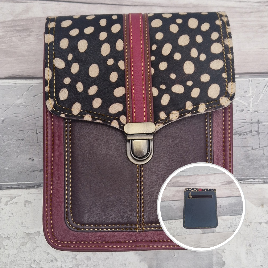 Raspberry leather crossbody bag with a textured panel of spot print. Accessed via a push clasp.