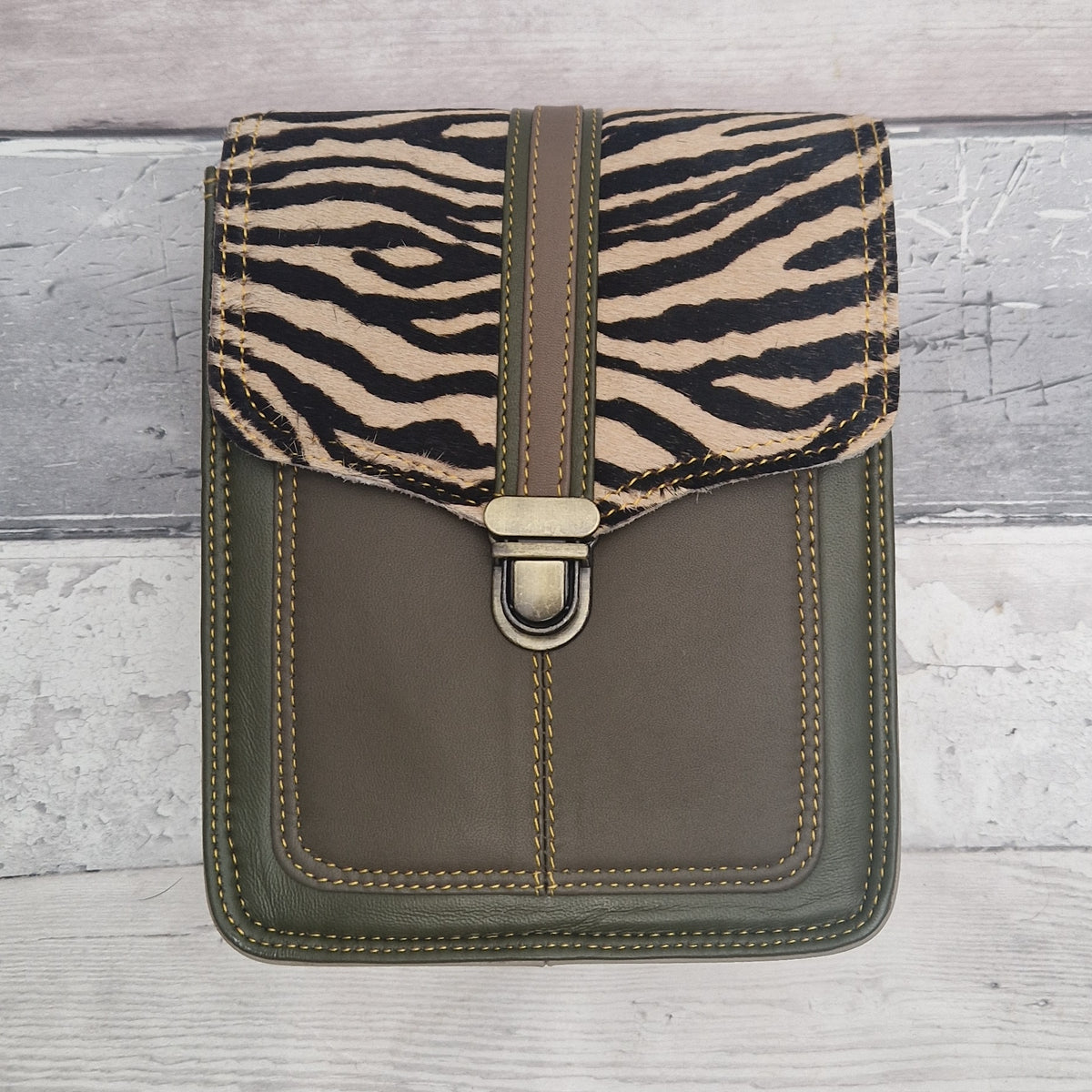 Green leather crossbody bag with a textured panel of zebra print. Accessed via a push clasp.