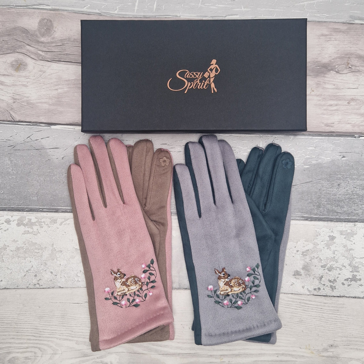 Pair of pink and gray gloves with embroidered woodland scene on a wooden surface, featuring 'Sassy Spirit' brand.