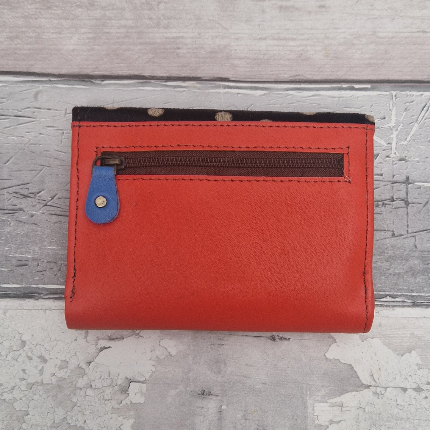 Red wallet with a blue zipper on a textured gray surface