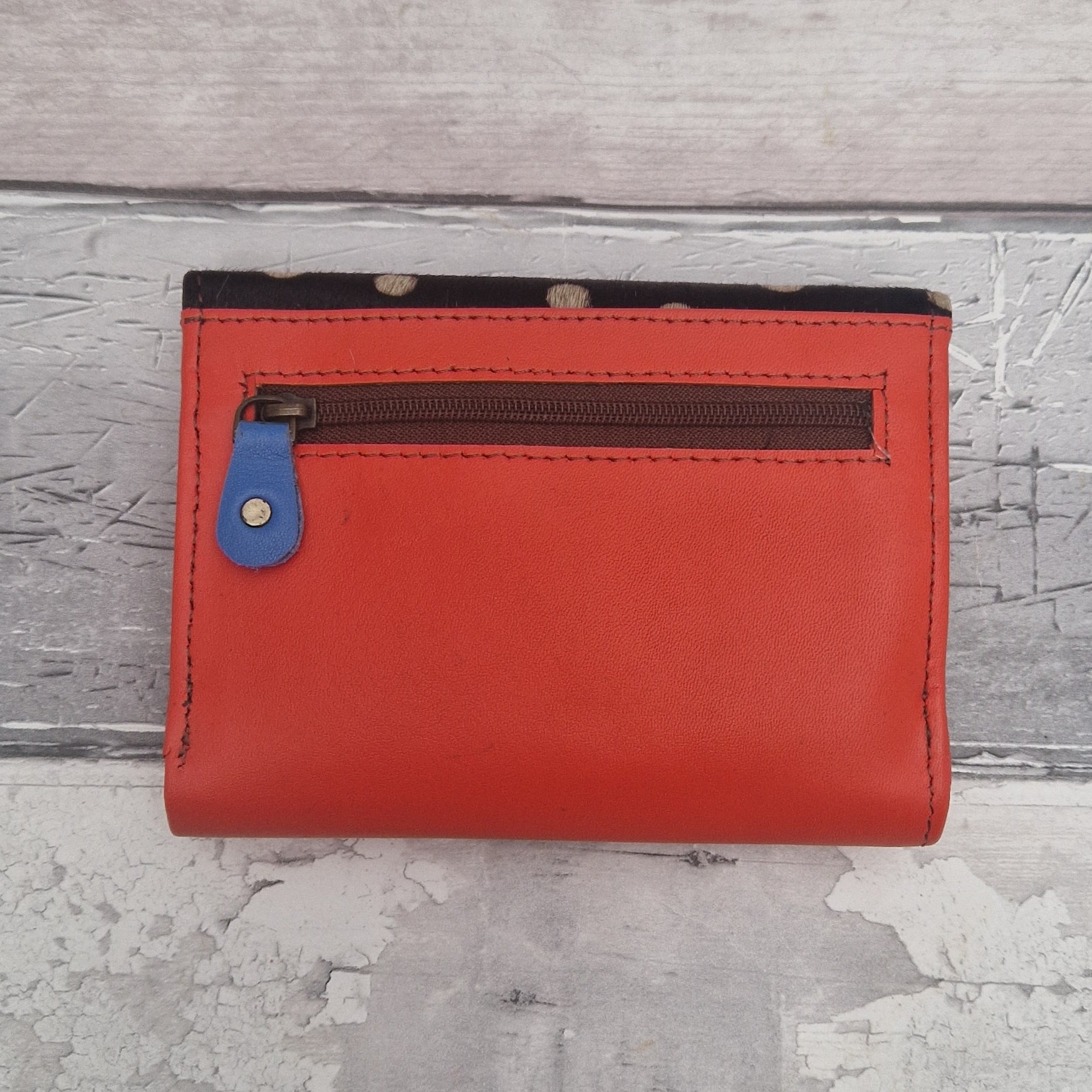 Red wallet with a blue zipper on a textured gray surface