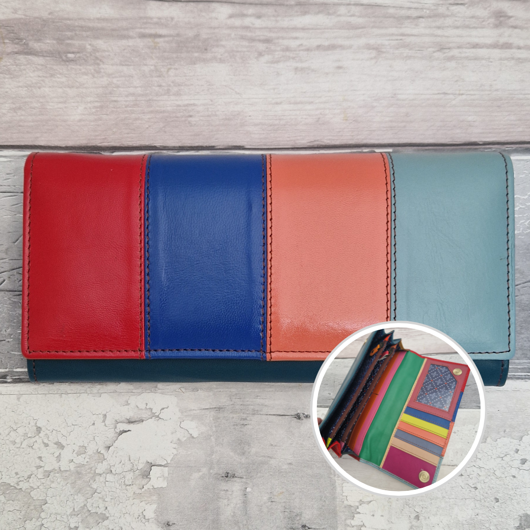 A four-panel leather wallet in vertical color blocks of red, royal blue, coral orange, and light blue, shown on a light gray wood-textured background with a circular inset showing other colorful wallets.