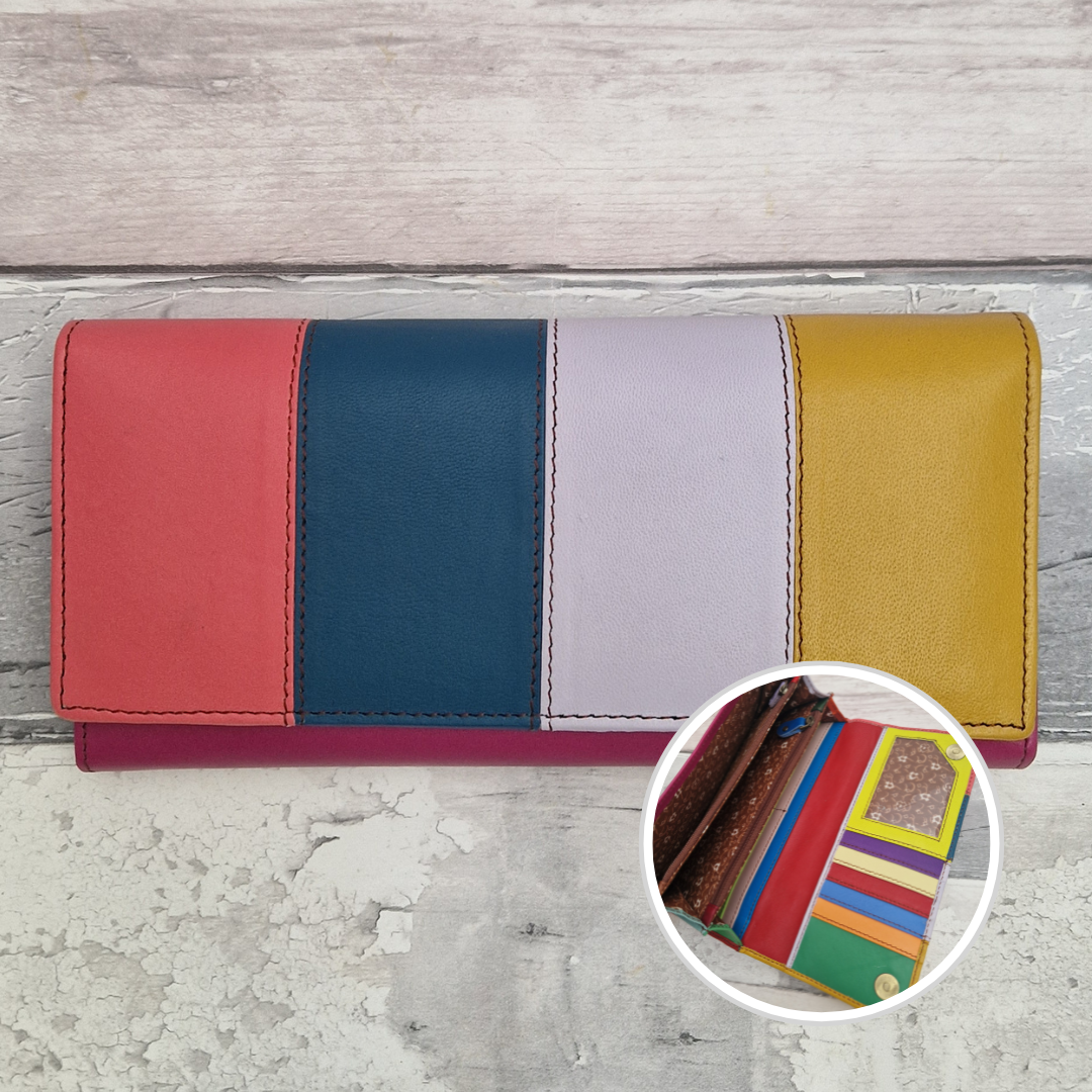 A multicolor leather wallet with vertical color-blocked panels in coral red, navy blue, pale lavender, and mustard yellow, shown on a light gray wood background with a circular inset showing the interior card slots.