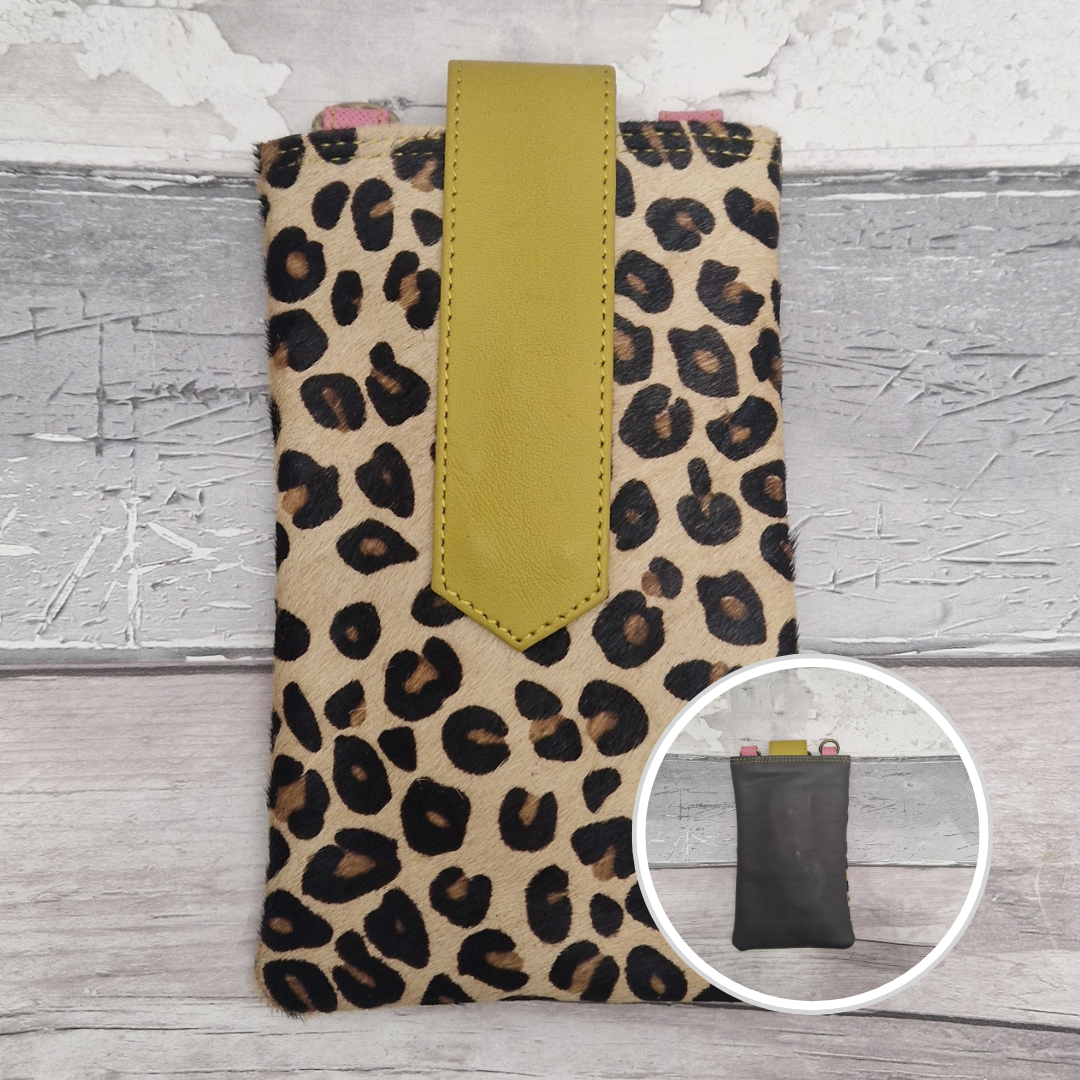 Leopard print phone case with a yellow strap on a textured surface