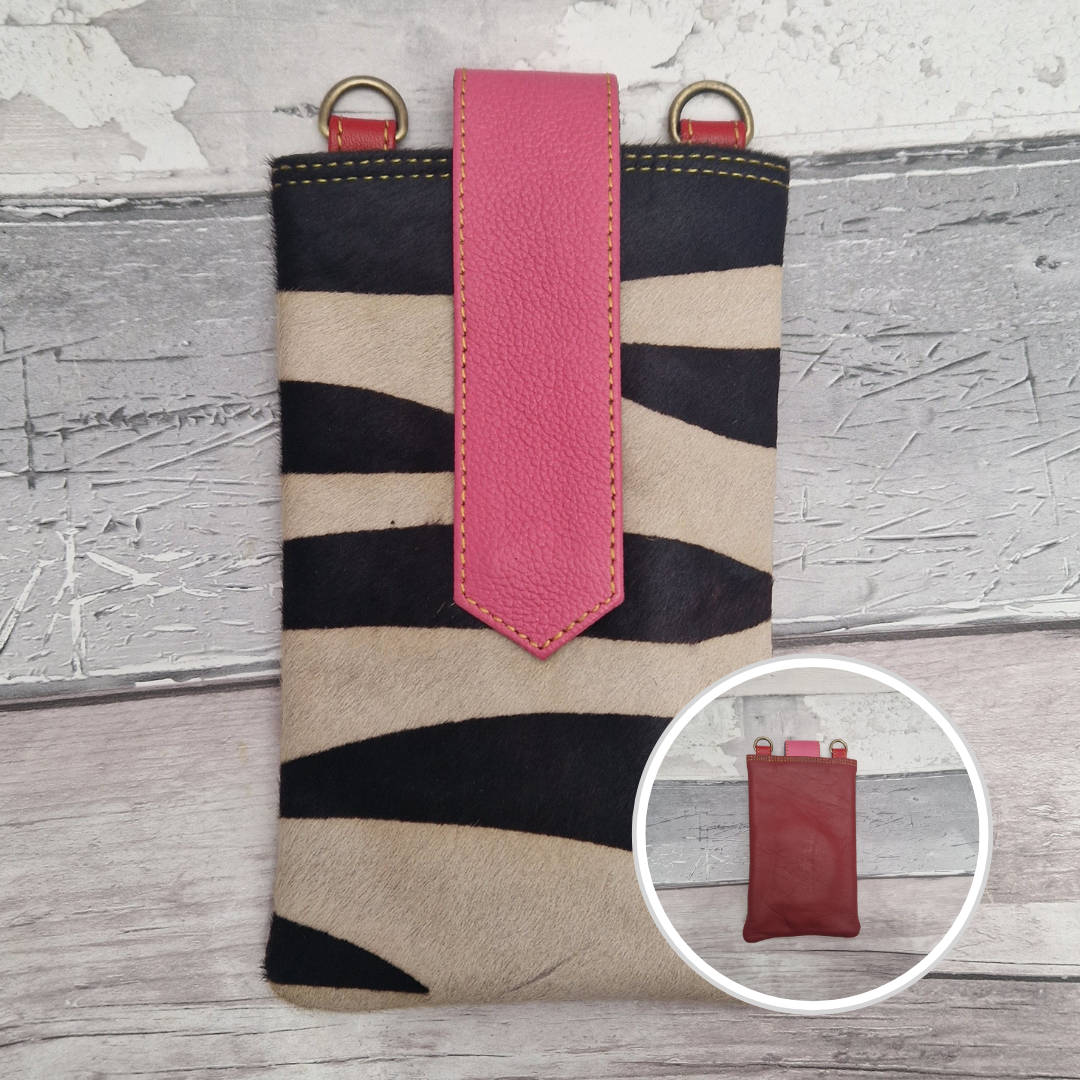 Phone case with zebra pattern and pink strap on a wooden surface