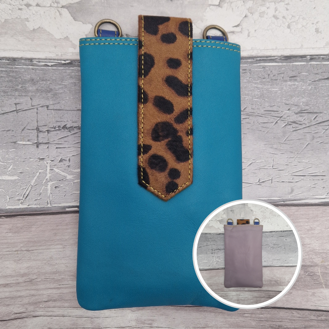 Blue phone case with leopard print strap on a wooden surface