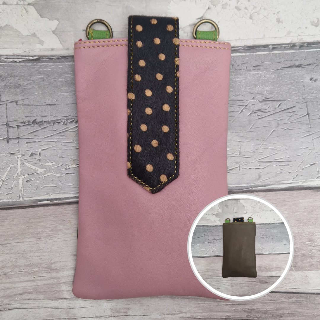Pink pouch with a black polka dot strap on a wooden surface