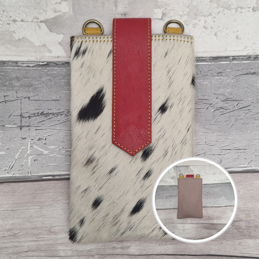 Phone case with cow print and red accent on a wooden surface