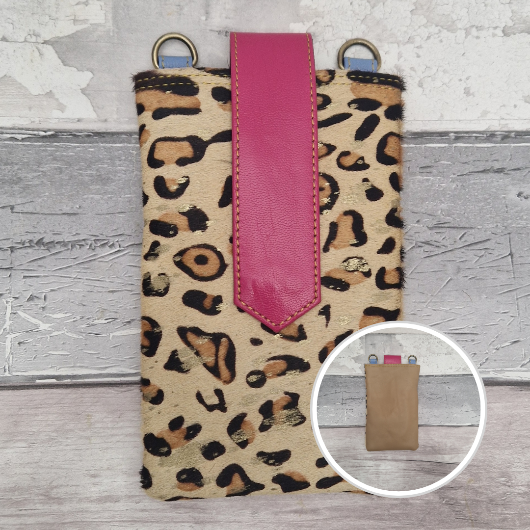 Leopard print phone case with a pink strap on a textured surface