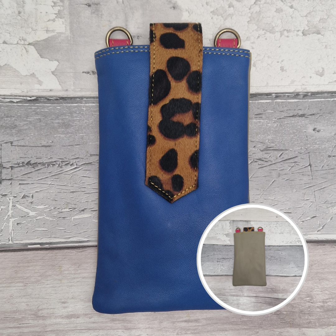Blue phone pouch with leopard print strap on a textured surface