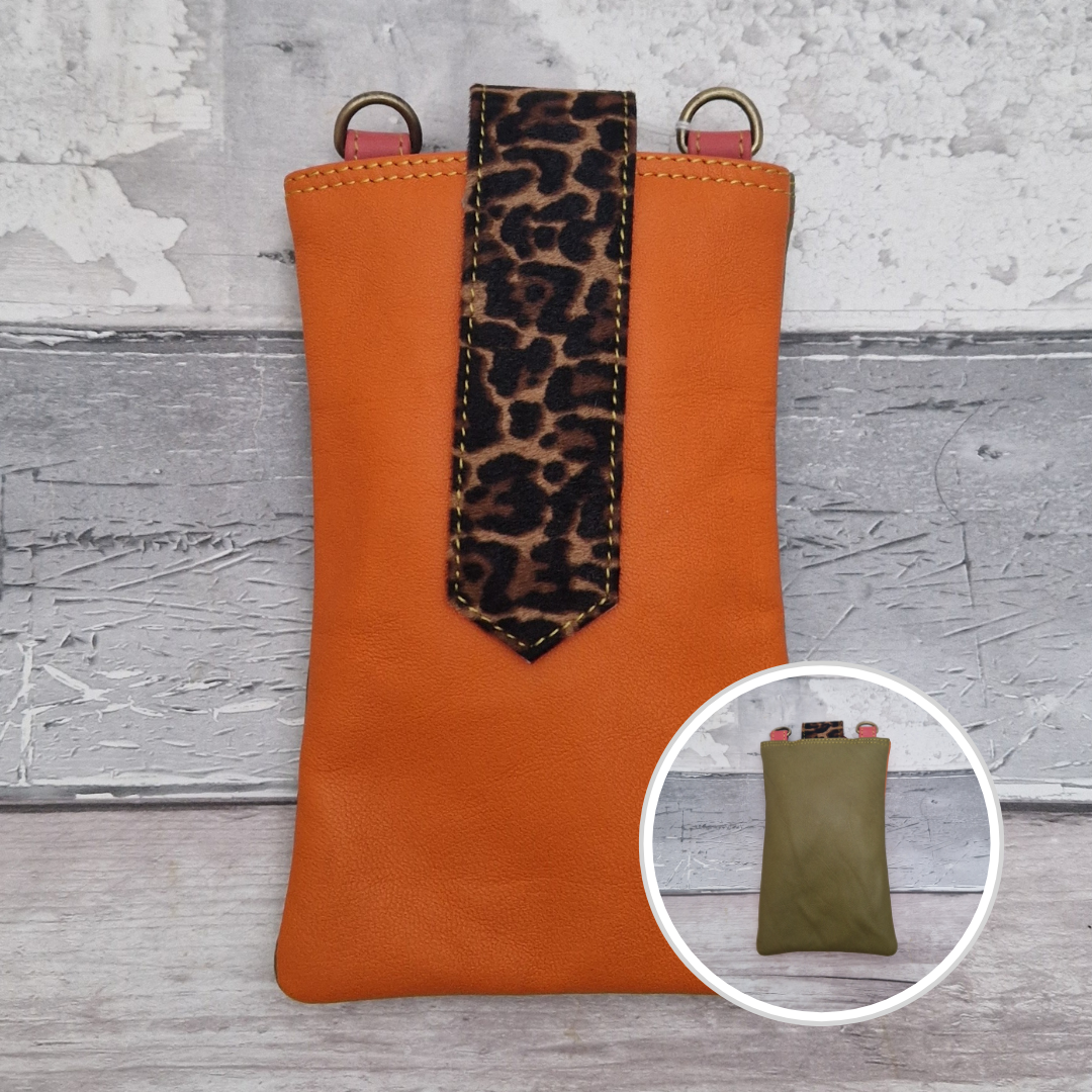 Crossbody body all leather pouch with a n orange exterior and jaguar print accent.