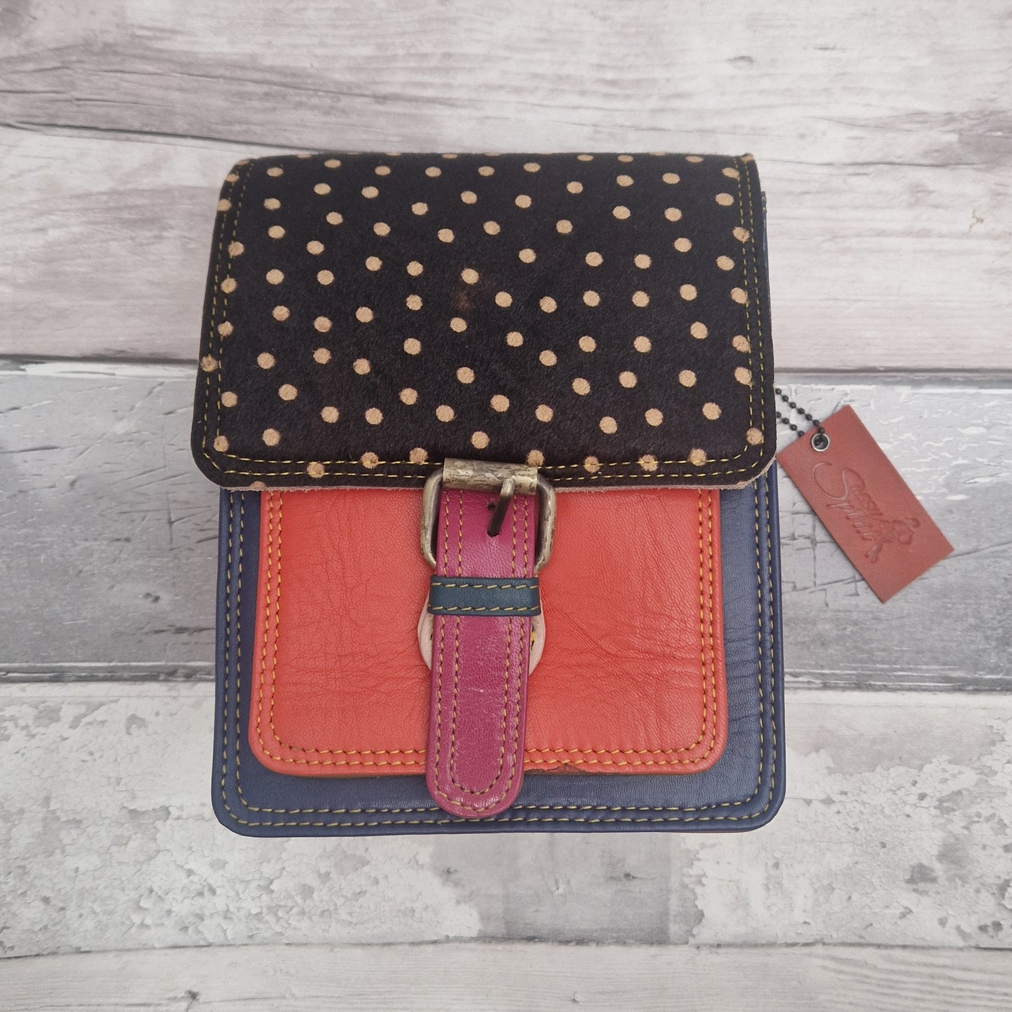 All leather mini satchel style bag with navy and orange panel finished with a textured dark spot print.