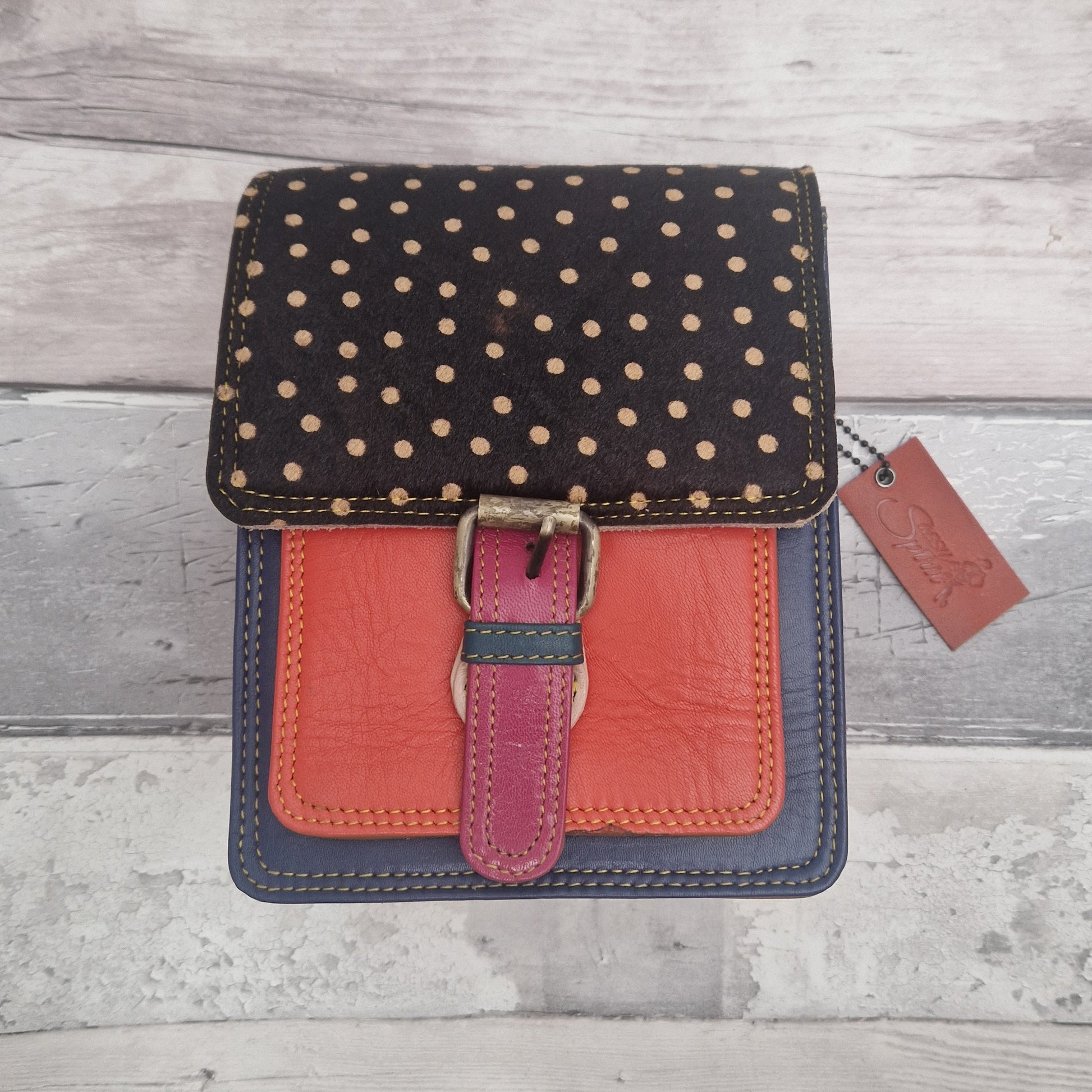 All leather mini satchel style bag with navy and orange panel finished with a textured dark spot print.