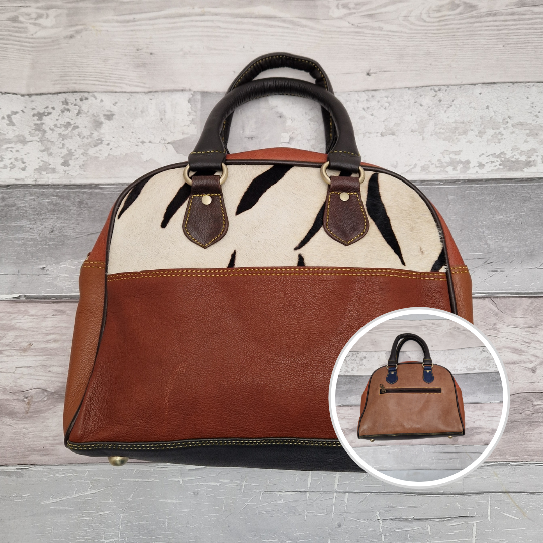 Bowling  bag style handbag made from leather off cuts in a variety of different colours. Textured panel of cow hide has been decorated with a striking Zebra print.