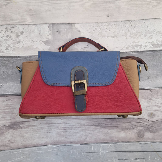 Multicolored leather handbag with blue, red, and beige sections on a wooden surface