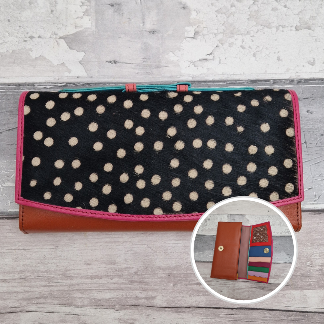 All leather purse with a rust and pink coloured exterior and textured panel of spot print.