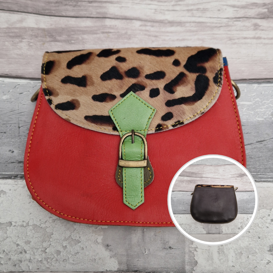 A red leather saddle-style handbag with an ocelot-print faux fur flap and a light green buckle detail, shown on a gray wood background with a circular inset showing the dark brown interior of the flap.