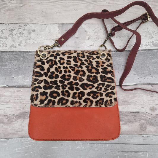 All leather modern messenger style bag with a bright orange panel and textured leopard print panel.