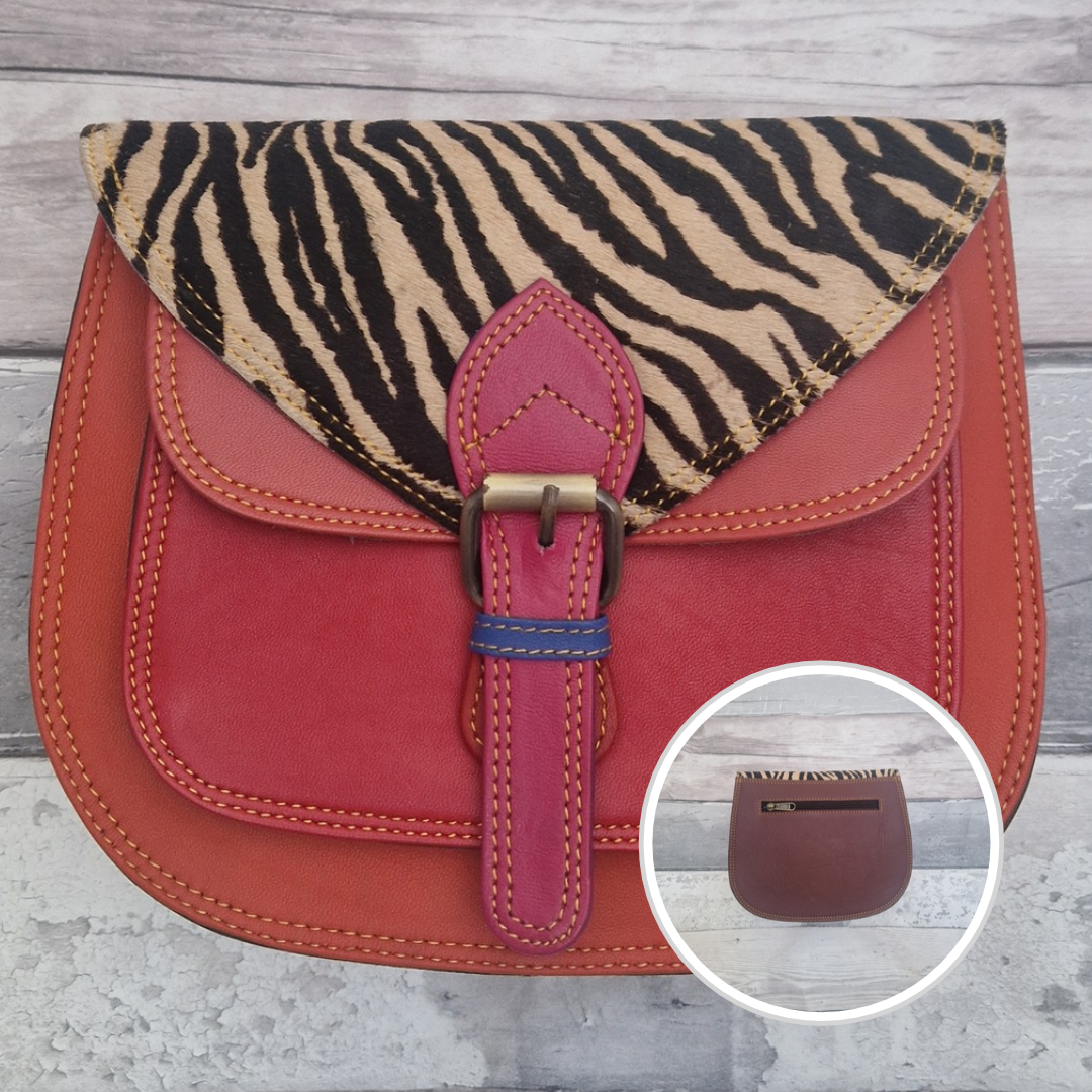 Saddlebag style bag in red coloured leather with contrasting coloured panels and a section of textured zebra Print