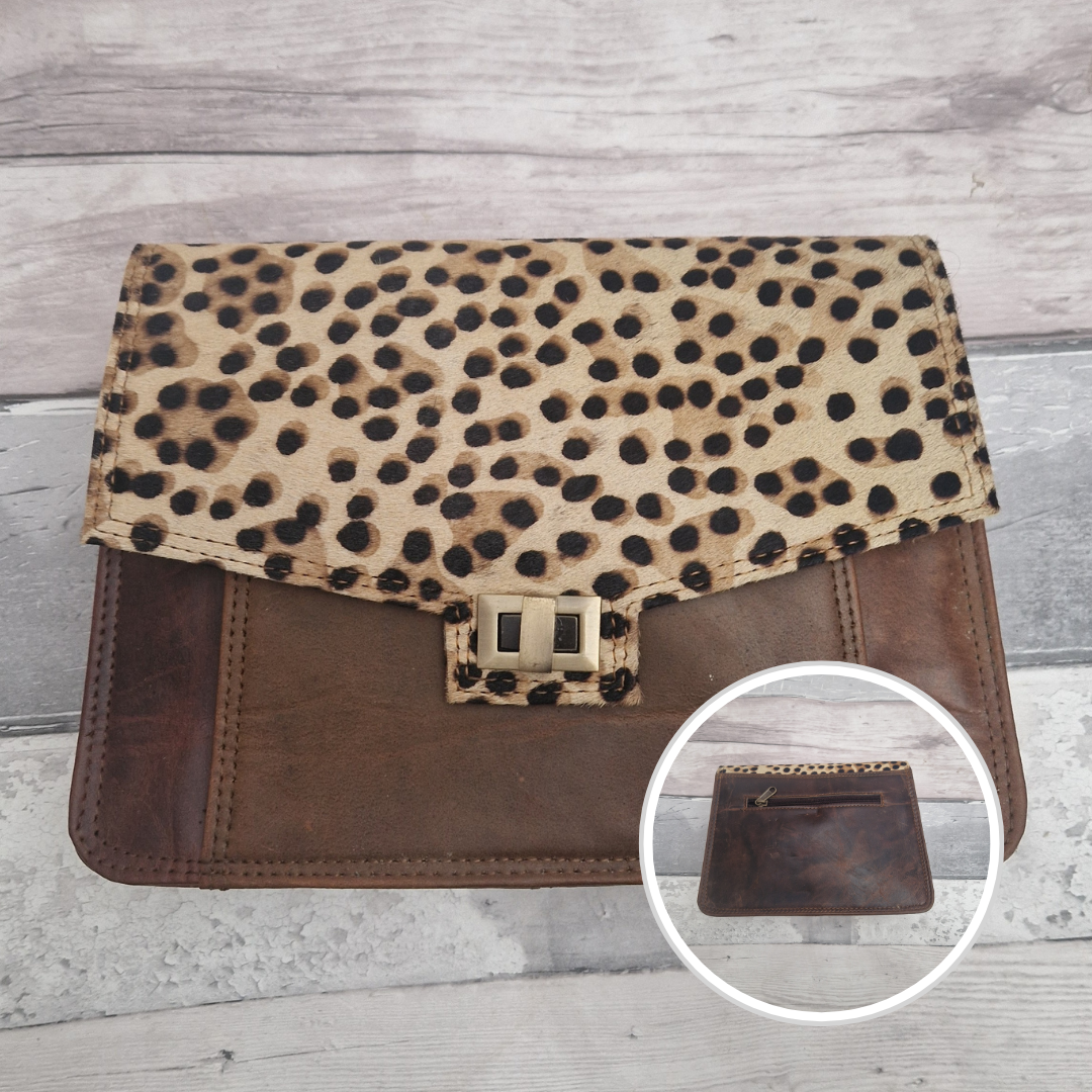 Cheetah print clutch bag with brown leather accents on a wooden surface