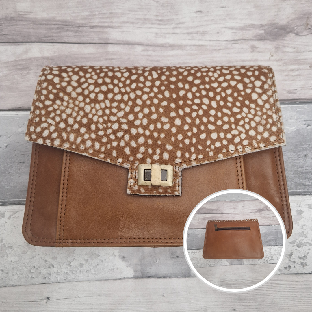 Tan leather clutch with animal print flap on a wooden surface